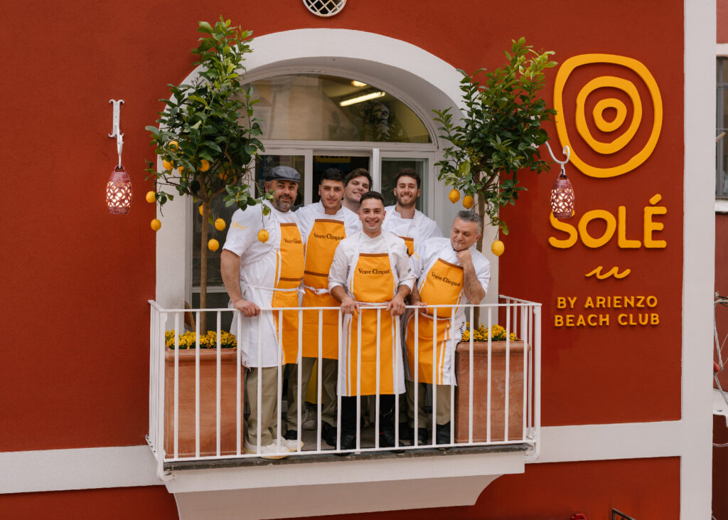 The Solé team in yellow aprons on the balcony of the red façade