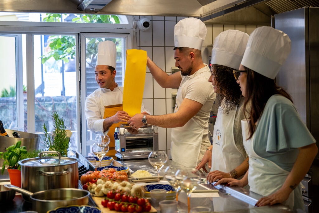 Chef and three guests in aprons and chef hats cooking together in the Solé kitchen