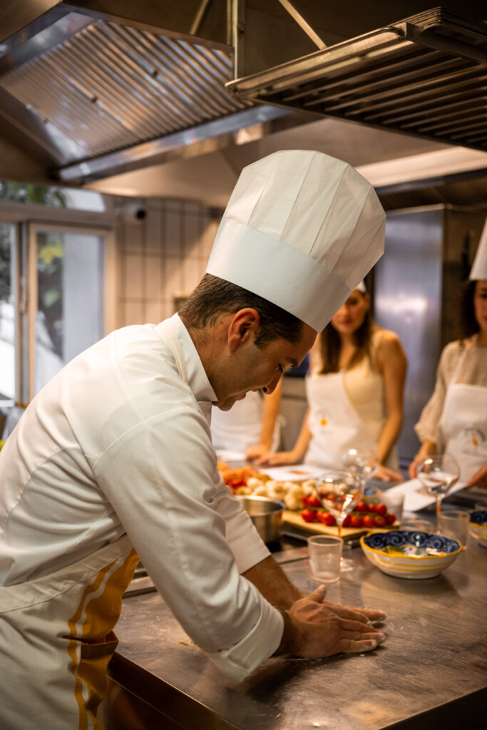 Chef kneading dough on the counter while guests look on