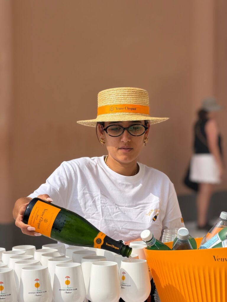 A Solé server in the Veuve Clicquot straw hat pouring Veuve Clicquot at the counter
