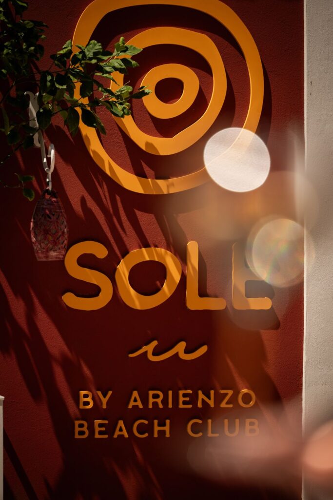 The Solé by Arienzo Beach Club sign in orange lettering on a red wall