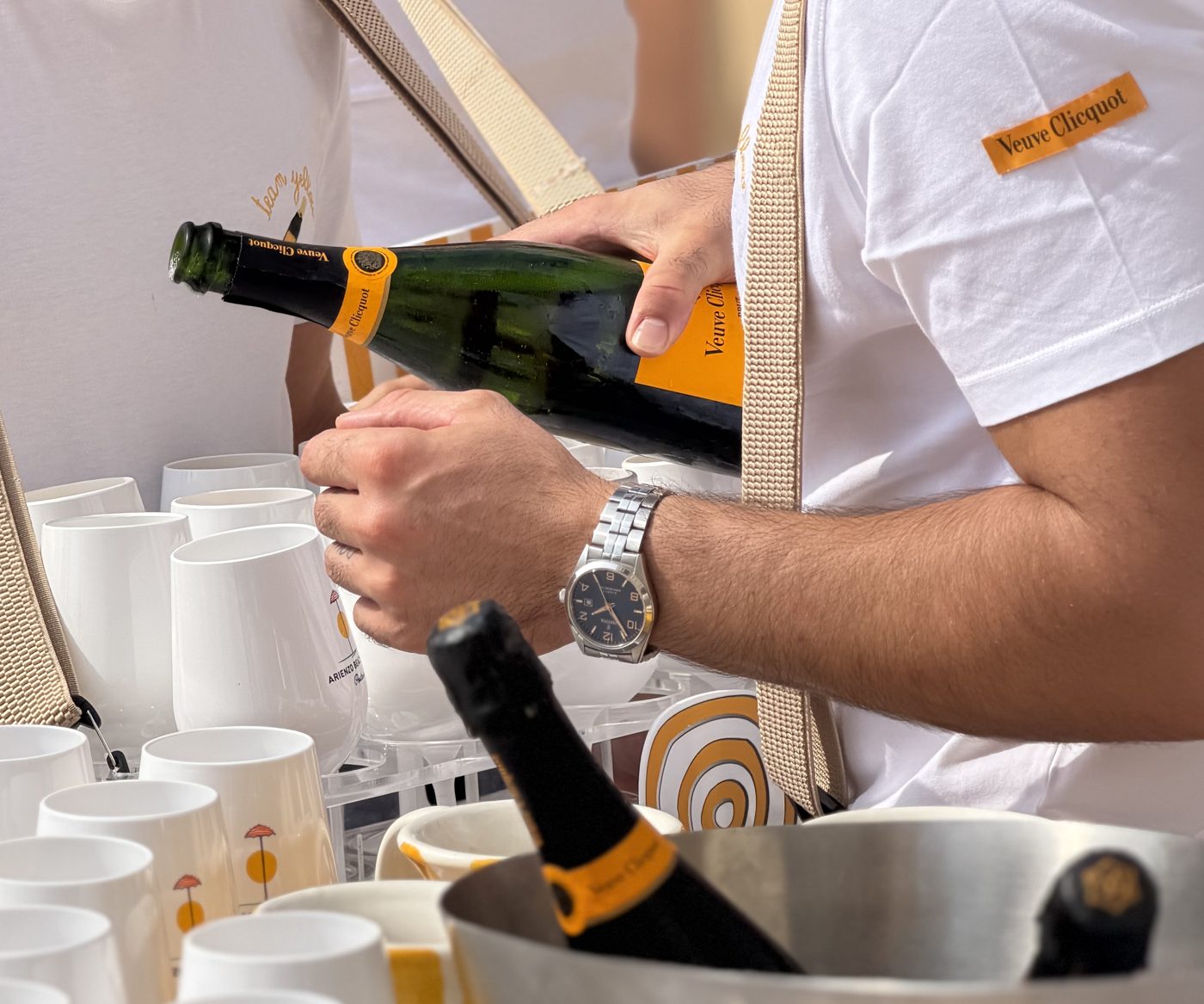 Close-up of a Solé server pouring Veuve Clicquot, bottle in hand, bucket below