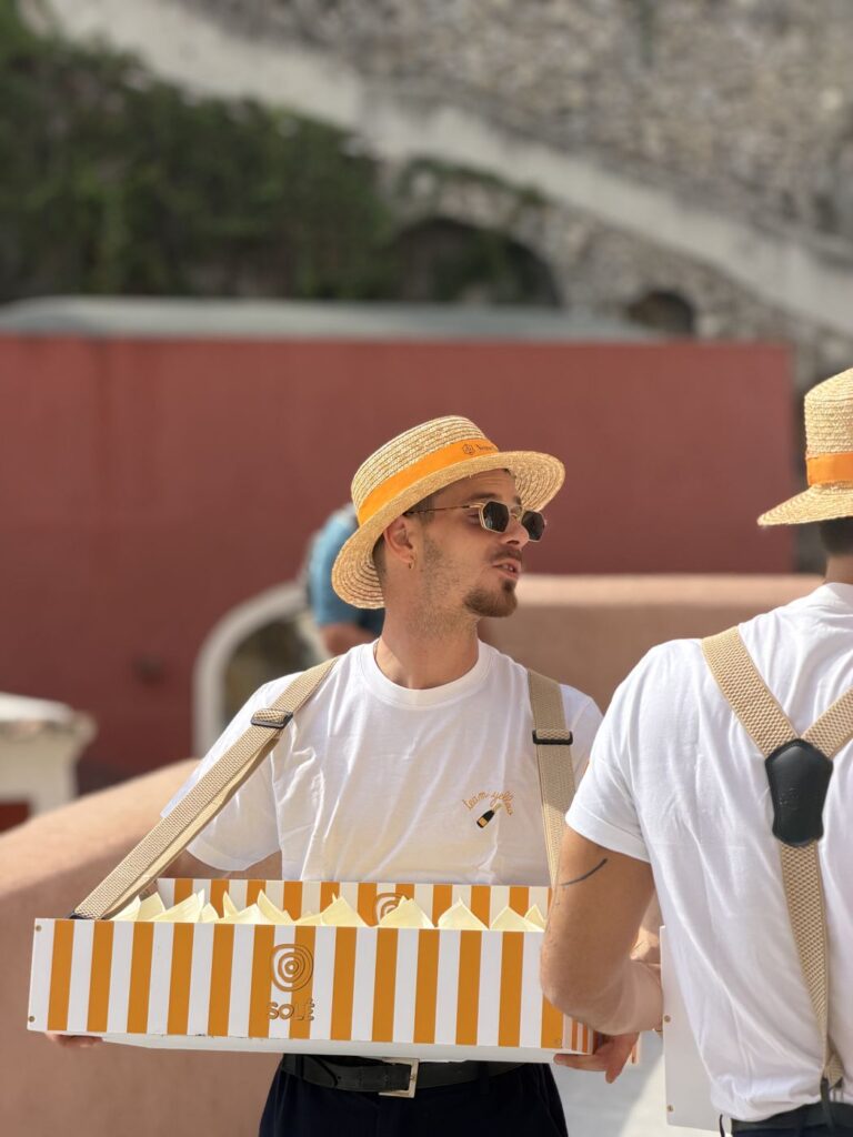 A server carrying a striped tray box of glasses past the red wall