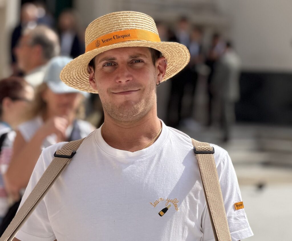 A Solé server in the straw hat with the Veuve Clicquot ribbon, white tee and tray straps